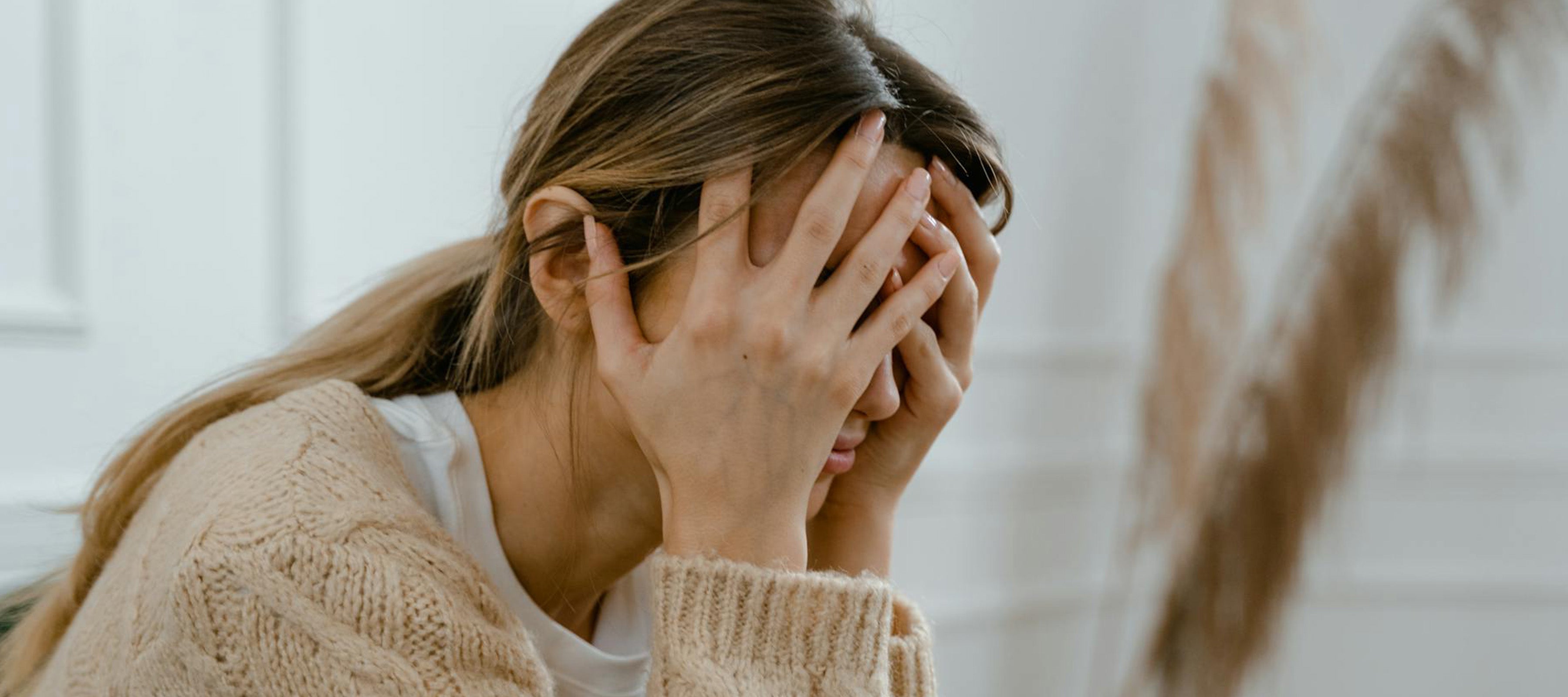 Young woman holding her head in distress, representing emotional symptoms after a period