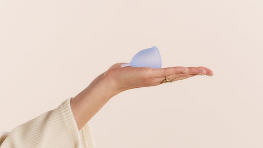 Hand holding blue menstrual cup.