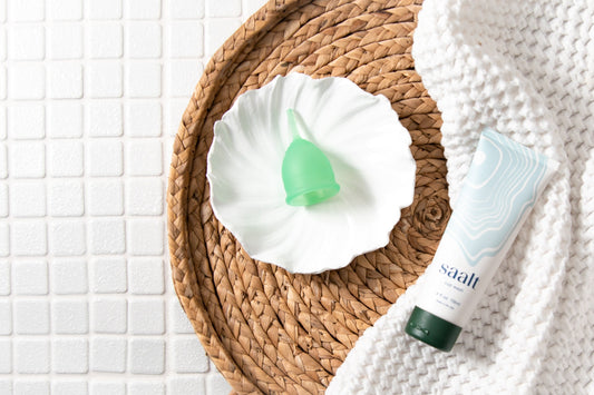 Green Saalt Cup and Saalt Wash on bathroom tile.