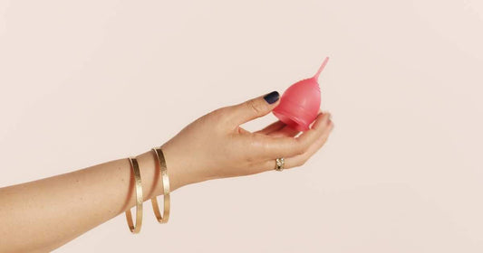 Hand holding pink menstrual cup.