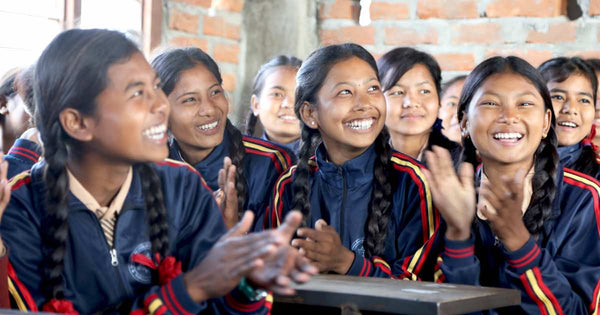 School girls clapping and smiling.