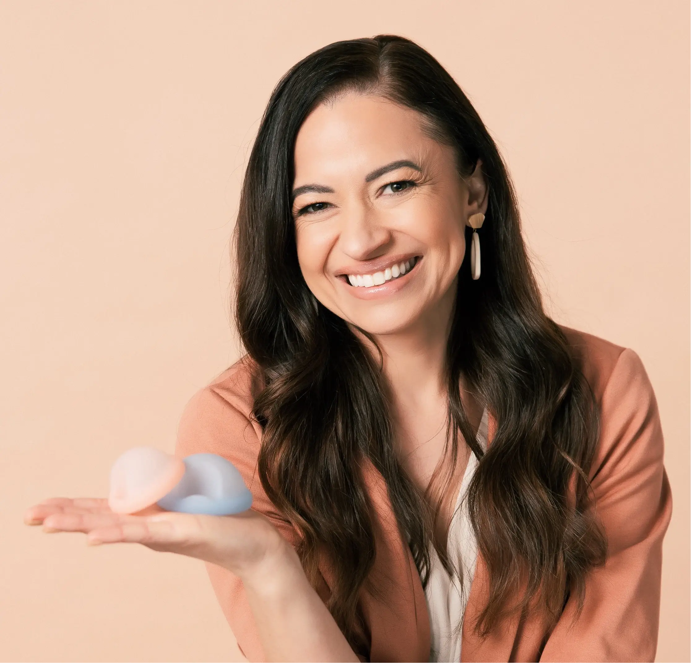 Saalt’s Founder and CEO, Cherie, smiling and holding two Saalt Discs in colors Coastal Blue and Sunset Coral.