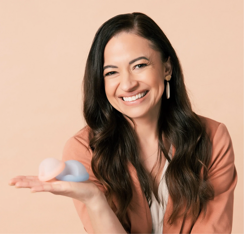 Saalt’s Founder and CEO, Cherie, smiling and holding two Saalt Discs in colors Coastal Blue and Sunset Coral.