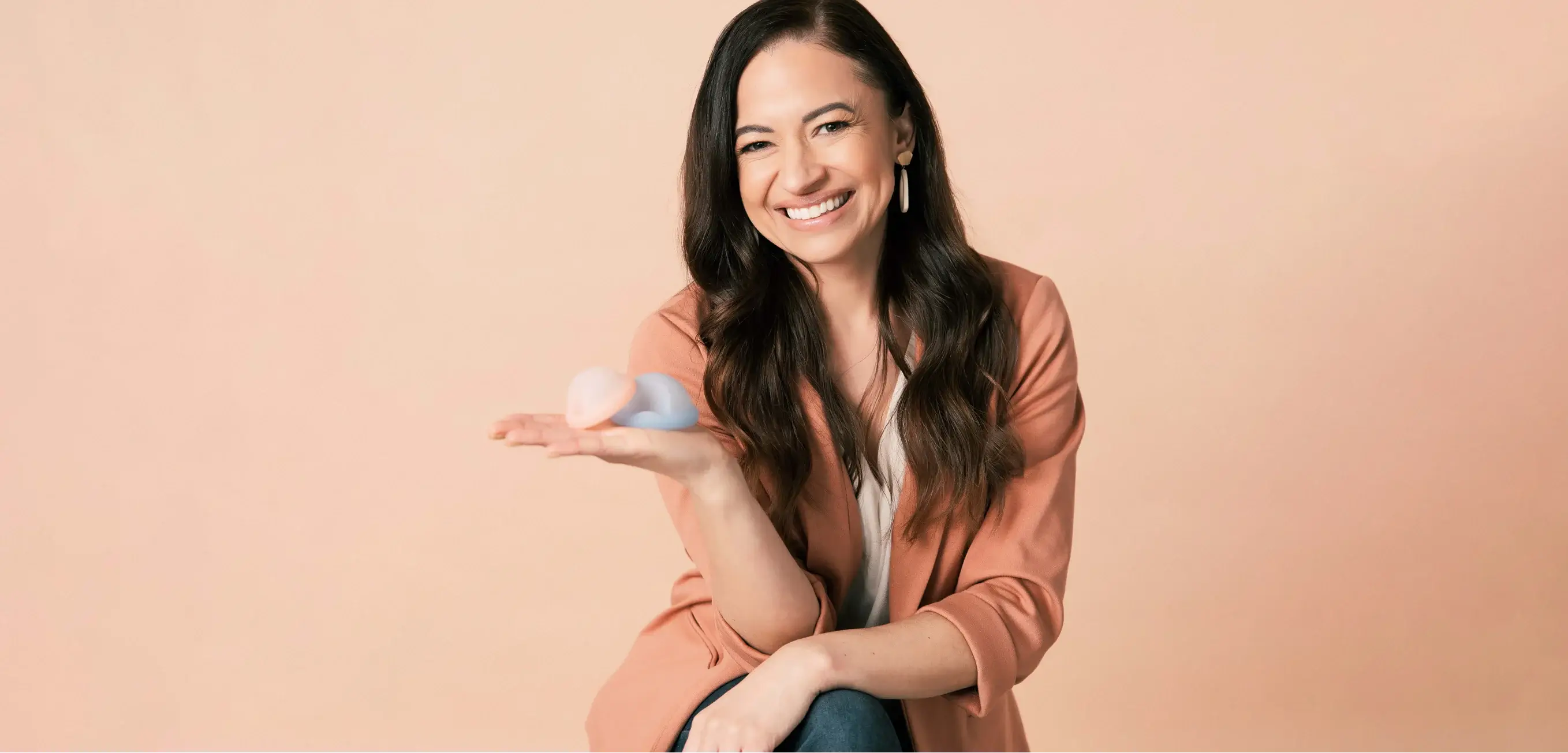 Saalt’s Founder and CEO, Cherie, smiling and holding two Saalt Discs in colors Coastal Blue and Sunset Coral.