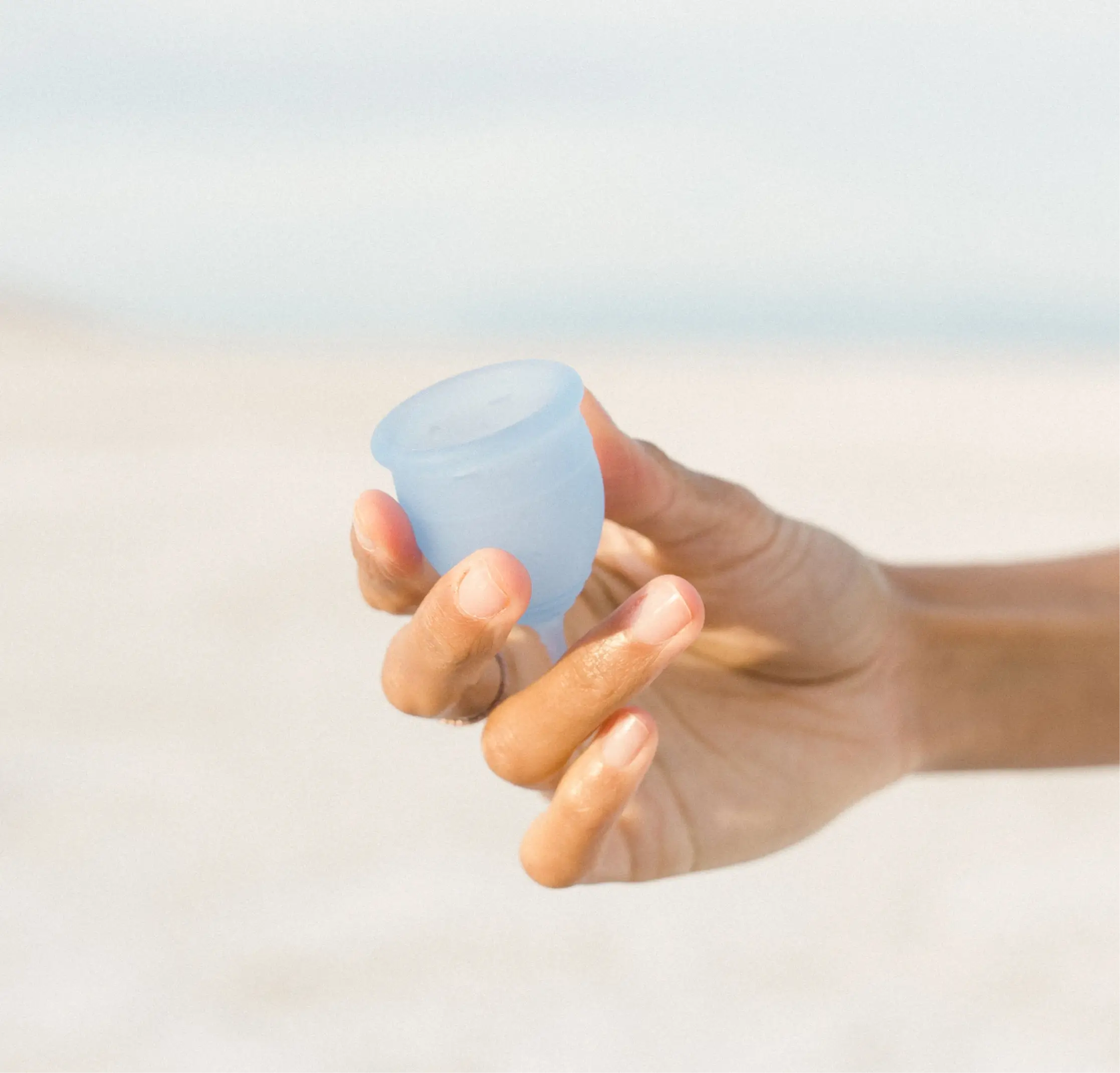 A hand holding Saalt’s Regular Menstrual Cup in color Ocean Blue.