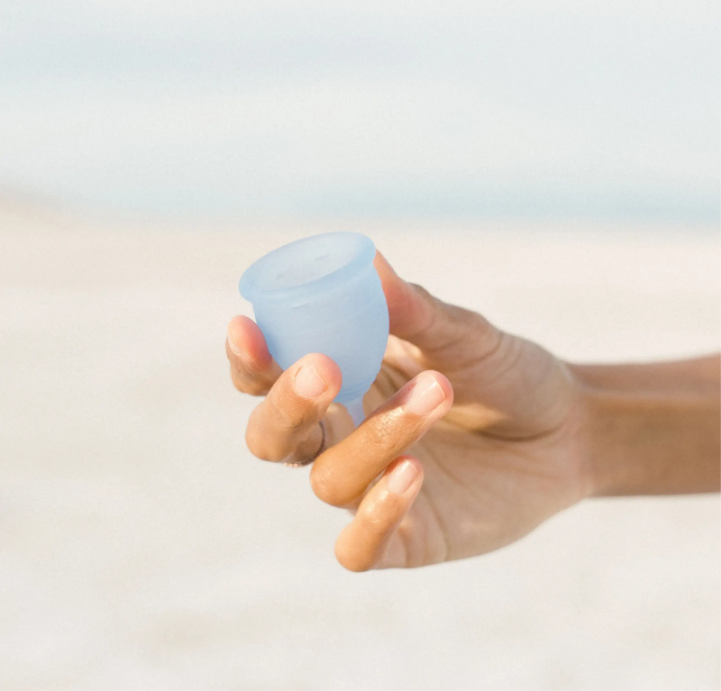 A hand holding Saalt’s Regular Menstrual Cup in color Ocean Blue.