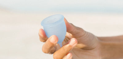 A hand holding Saalt’s Regular Menstrual Cup in color Ocean Blue..